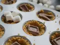 S'mores i ugn förbereds i en muffinsform med krossade kex, chokladbitar och marshmallows.