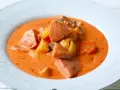 A hearty bowl of korvsoppa with sausage, potatoes, and carrots in a creamy orange broth.
