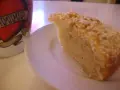 En bit saftig sockerkaka med kardemumma, toppad med nötter, ligger på en vit tallrik bredvid en mugg med texten "MAMMA".