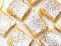 Citronkaka i långpanna, pudrad med florsocker, skuren i fyrkanter. En citronskiva syns i övre vänstra hörnet.