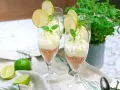 Key lime pie in glasses with whipped cream, lime slices, and mint.