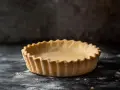 En gyllene, glutenfri pajdeg med vågiga kanter, redo att fyllas med din favorittårta.
