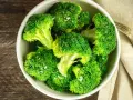 En skål med nykokt, grön broccoli, strödd med flingsalt. En gaffel ligger bredvid på en beige duk.