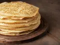 En hög med gyllene pannkakor på en träbricka. Perfekt för att frysa in och njuta av senare.