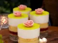 Fyra små prinsesstårta i glas, dekorerade med rosa marsipanrosor och gul marsipanlock. En festlig dessert.