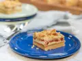 A slice of rhubarb cheesecake with a crumb topping on a blue plate.