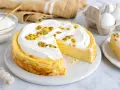 En krämig mango cheesecake med fluffig topping och passionsfrukt. En bit är redan uppskuren.