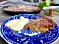 A slice of rhubarb pie with a dollop of cream on a blue and white patterned plate.
