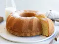 A golden-brown bundt cake dusted with powdered sugar, with a slice removed.