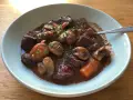 En skål med mustig boeuf bourguignon, fylld med mört kött, champinjoner och morötter, toppad med persilja.