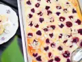 En saftig hallonpaj med vit choklad och mandelflagor, serverad på en vacker tallrik med vispgrädde.
