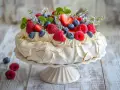 Vacker pavlova med grädde och färska bär, perfekt att dekorera tårta med.