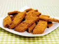 En hög med gyllene, krispiga kola kakor på en vit tallrik, redo att avnjutas.
