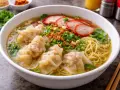 En skål med nudlar, wontons, skivat fläsk och grönsaker. Perfekt för att avgöra hur mycket soppa per person.