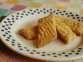 Tre gyllene glutenfria kolakakor ligger på en vit tallrik med blå prickar. De har ett rutmönster på ovansidan.