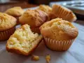 Gyllene muffins, perfekta för ett glutenfritt fika. En är uppdelad och visar en fluffig insida.