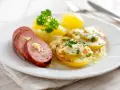 Skivad falukorv med smör och persilja, serverad med kokt potatis och en krämig sås. Bra att veta om man kan frysa falukorv.