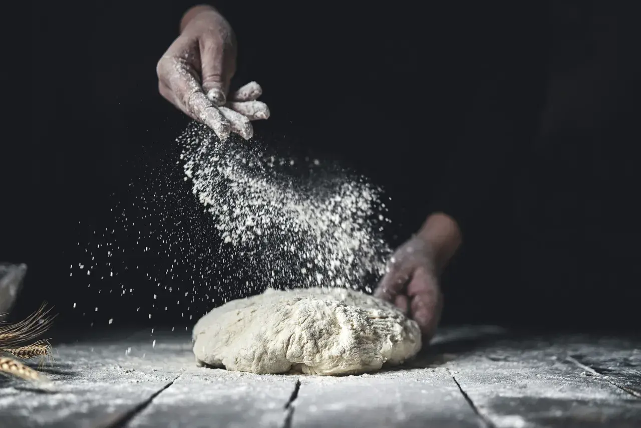 Händer strör mjöl över deg. En berättelse om svenskt bröd och kärleken till bakning med bra **bread flour svenska**.