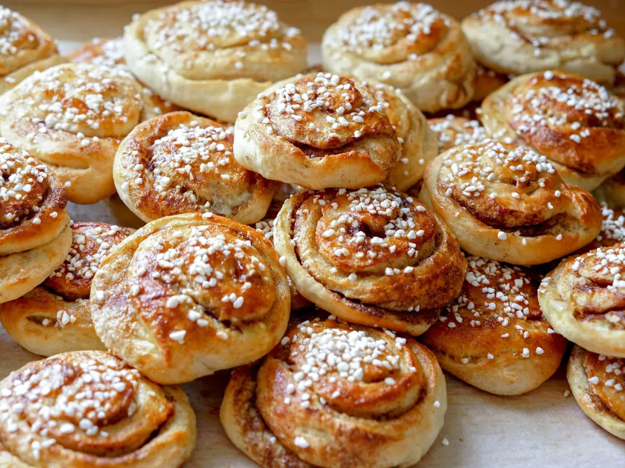 En hög med nybakade kanelbullar, strösslade med pärlsocker. Kanske bakade av Camilla Hamid för en fika.