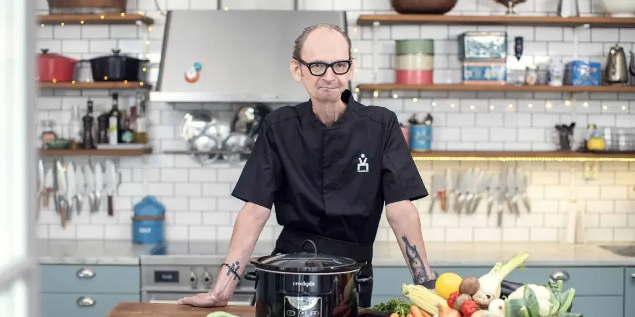 Erik Videgård i köket med en slow cooker och färska grönsaker.