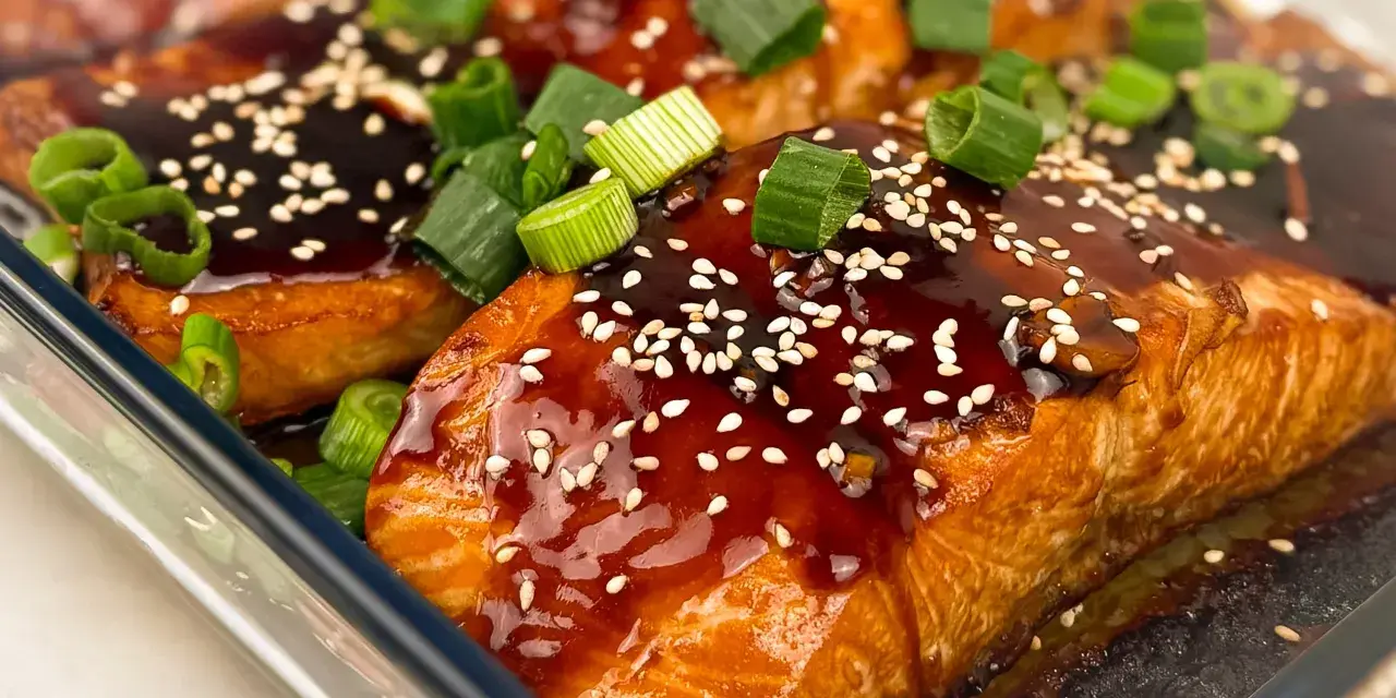 Saftiga filéer av asiatisk lax, glaserade med en mörk sås, toppade med sesamfrön och färsk salladslök.