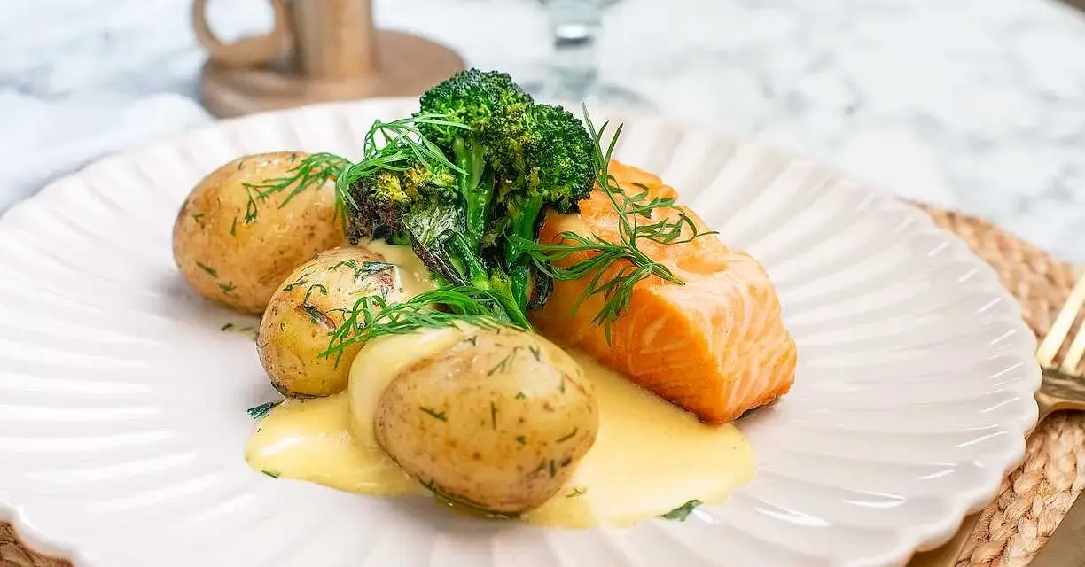En saftig bit lax med krämig sås, serverad med små, dillkryddade potatisar och fräsch broccoli. En klassisk svensk rätt med lax och potatis.
