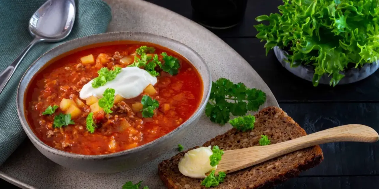 En värmande köttfärssoppa utan tomat, toppad med en klick gräddfil och färsk persilja. Serveras med grovt bröd och smör.