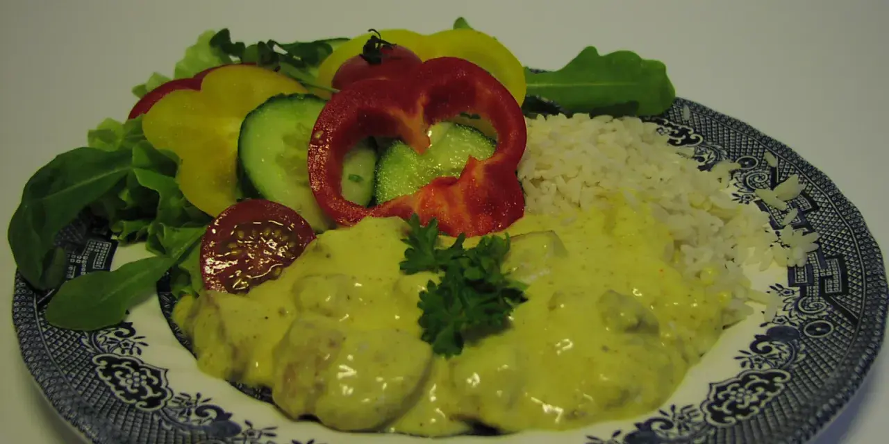 Enkel currysås över kyckling med ris och en fräsch sallad av paprika, gurka och tomat.