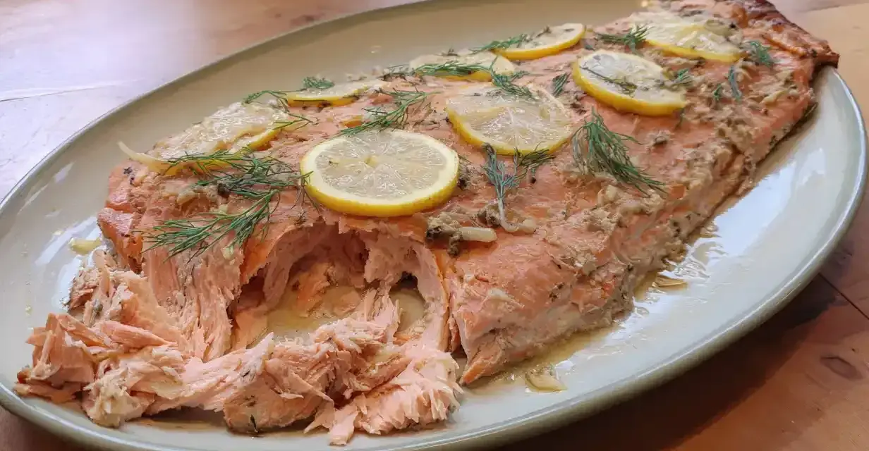 Helstekt lax i ugn, toppad med citronskivor och dill. Perfekt för en festlig middag.