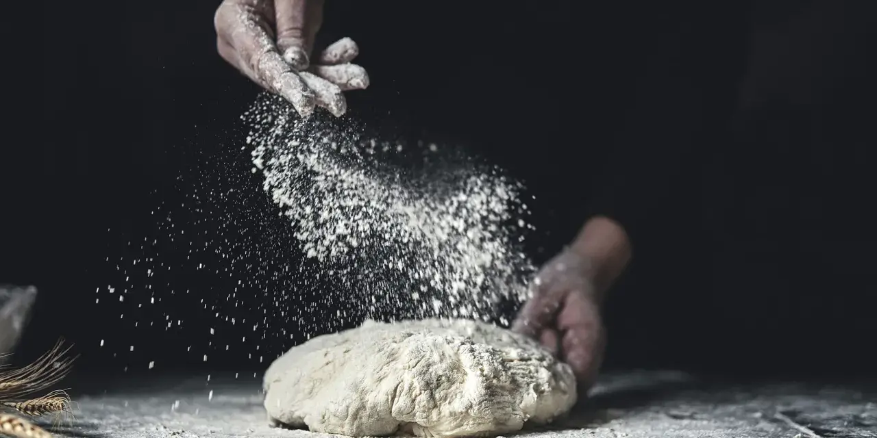 Händer strör mjöl över deg. En berättelse om svenskt bröd och kärleken till bakning med bra **bread flour svenska**.