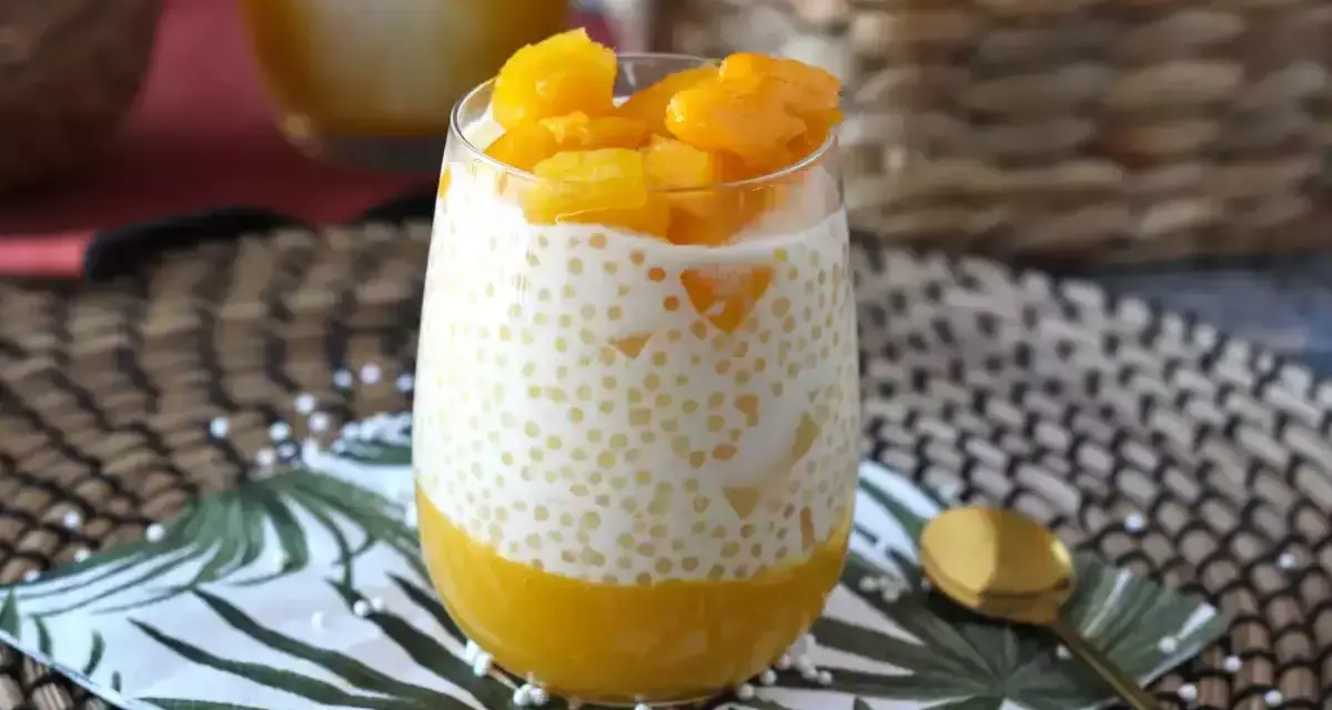 En smaskig mango sago-dessert i ett glas, toppad med färsk mango. En perfekt tropisk njutning.