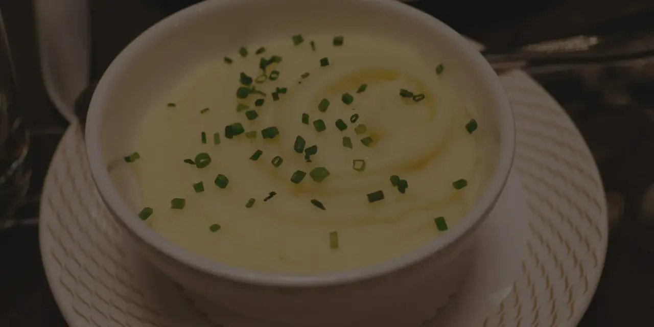 Krämig potatismos i en vit skål, garnerad med gräslök. Perfekt för att frysa potatis och njuta av senare.