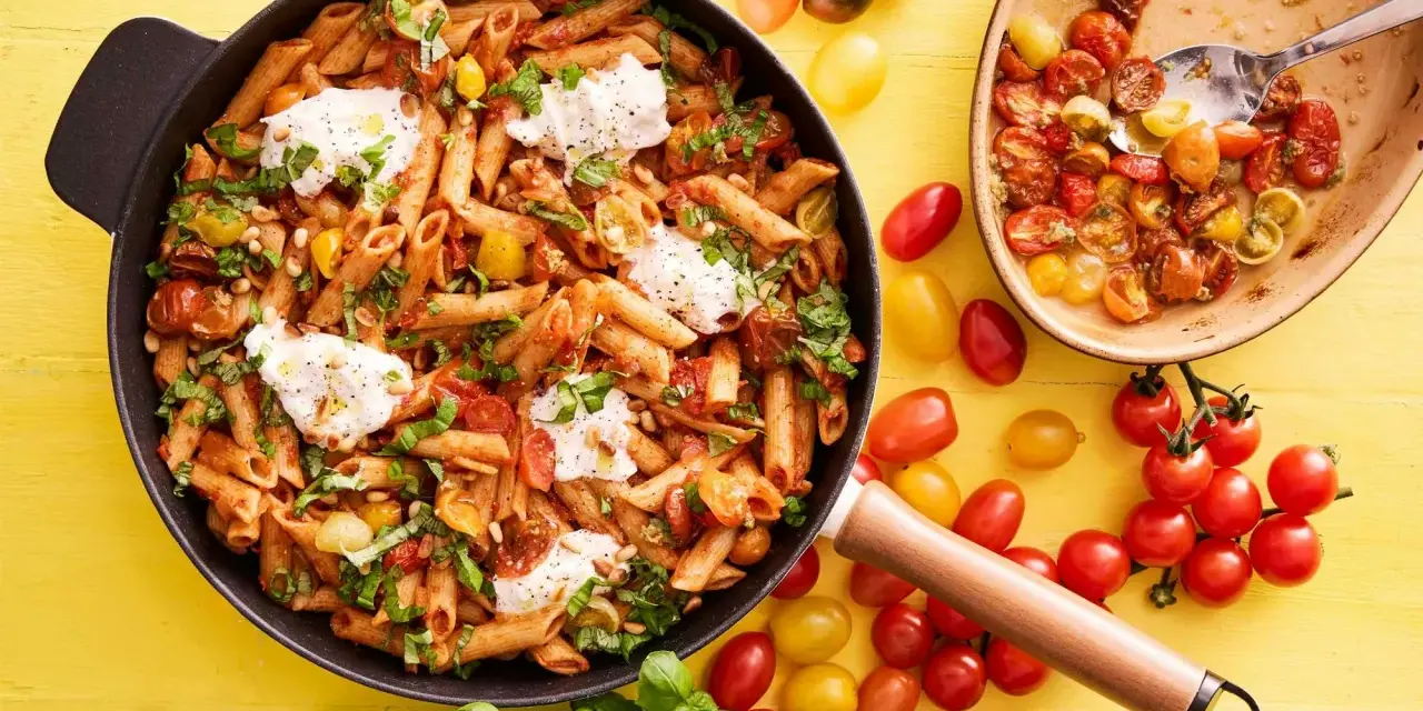 En panna med penne, körsbärstomater, basilika och mozzarella. En härlig vegetarisk mat som ser utsökt ut.