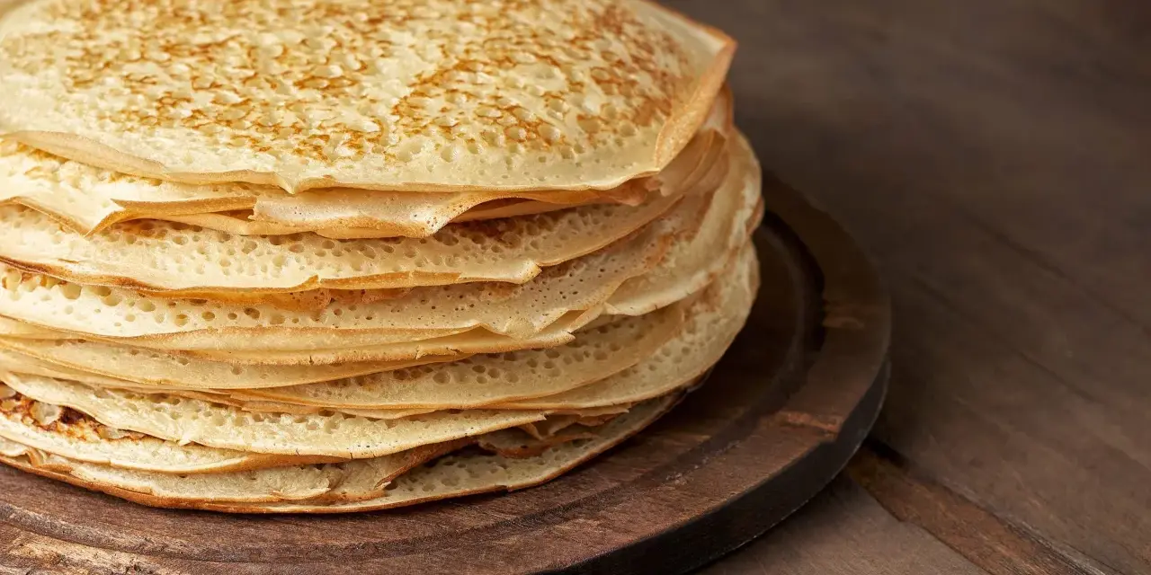 En hög med gyllene pannkakor på en träbricka. Perfekt för att frysa in och njuta av senare.