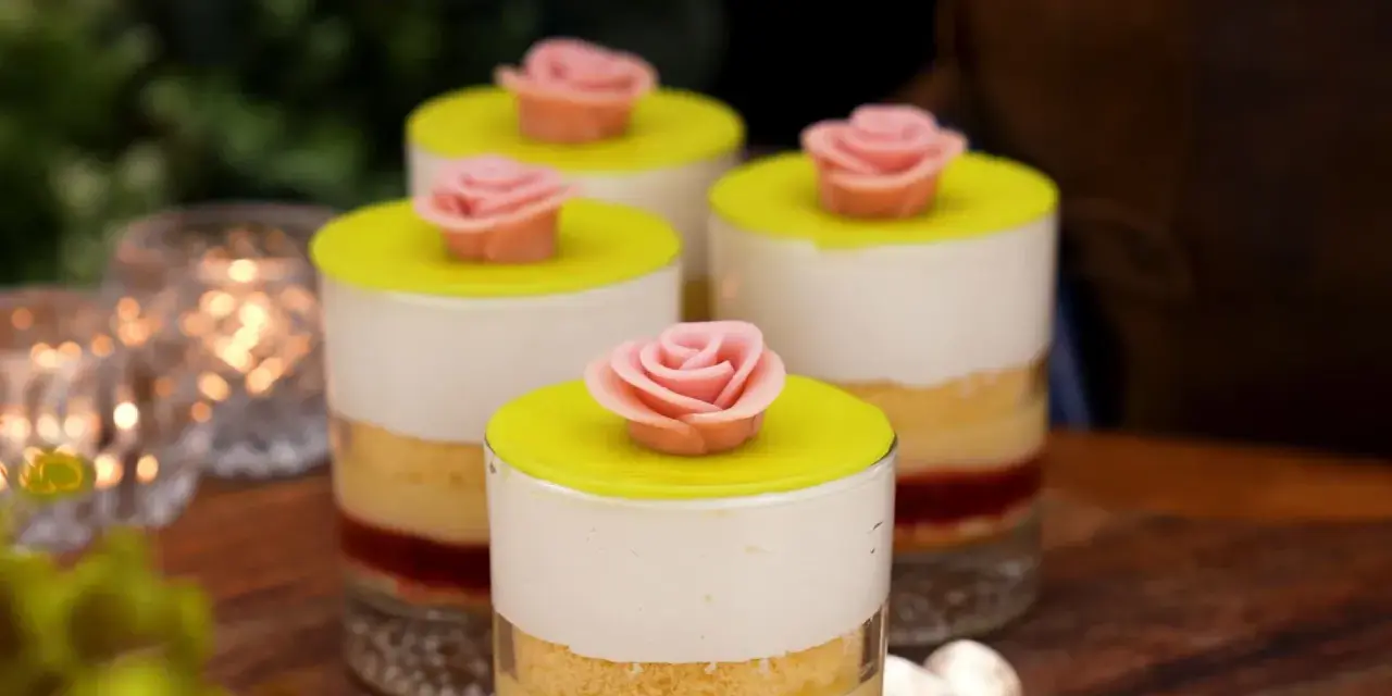 Fyra små prinsesstårta i glas, dekorerade med rosa marsipanrosor och gul marsipanlock. En festlig dessert.