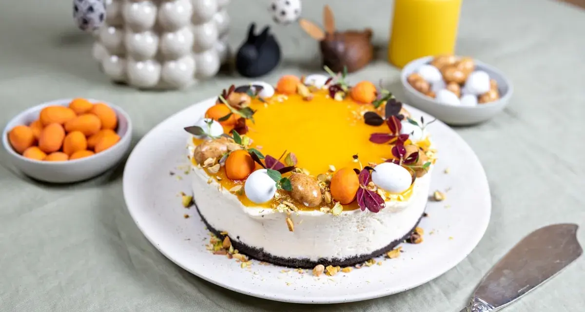 En vacker cheesecake påsk med gul topping, dekorerad med påskägg och nötter. Perfekt för påskfirandet!