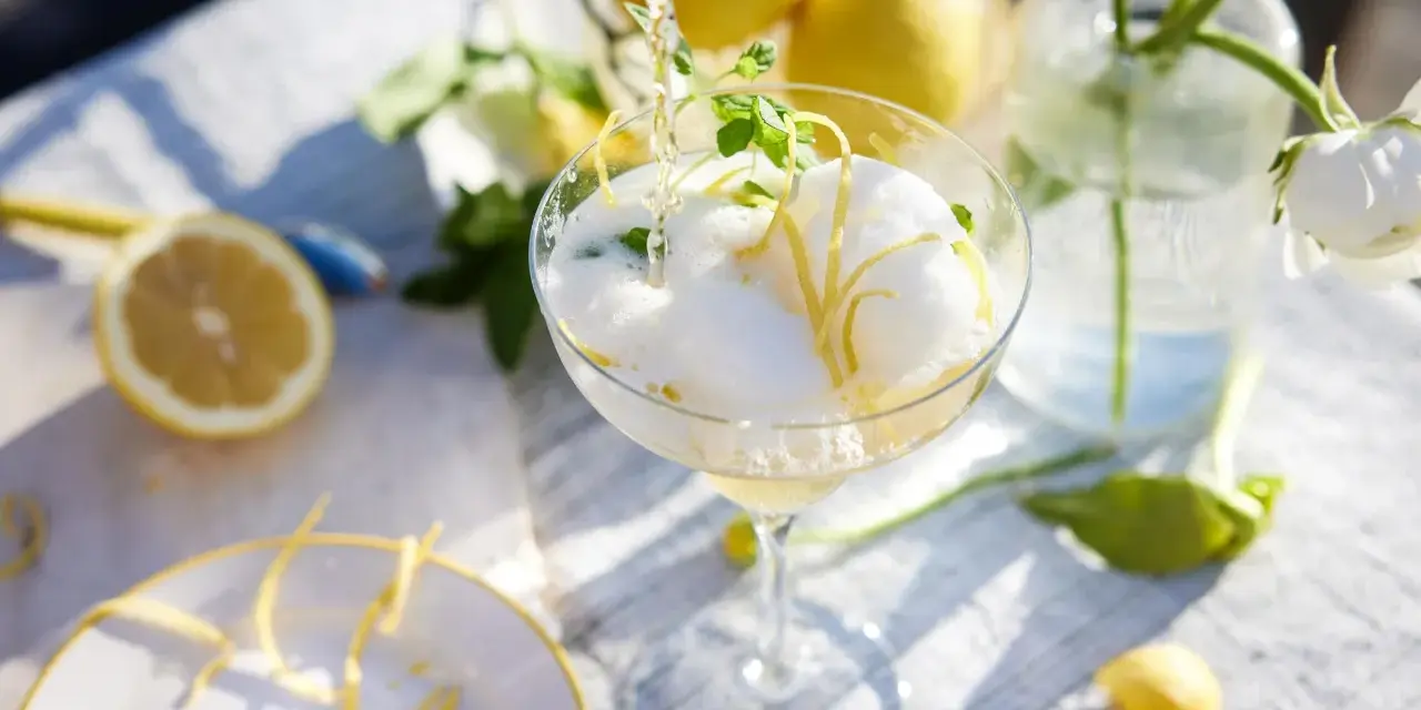 En bubblig drink med citronskal och mynta hälls upp i ett glas. Perfekt att bjuda på fika till många.