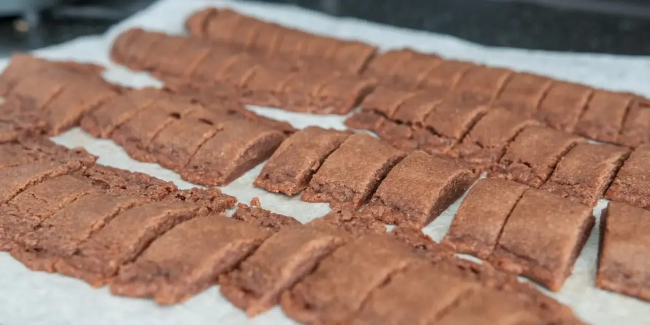 Rader av nybakade, sega chokladsnittar ligger på ett bakplåtspapper, redo att avnjutas.