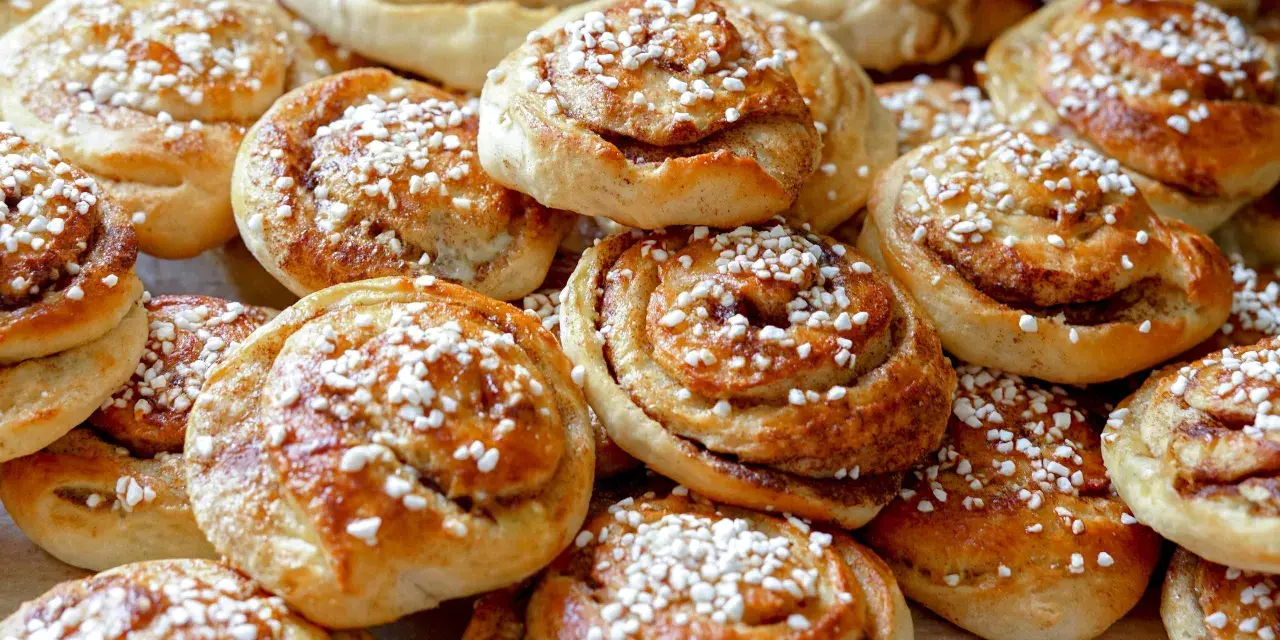 En hög med nybakade kanelbullar, strösslade med pärlsocker. Kanske bakade av Camilla Hamid för en fika.