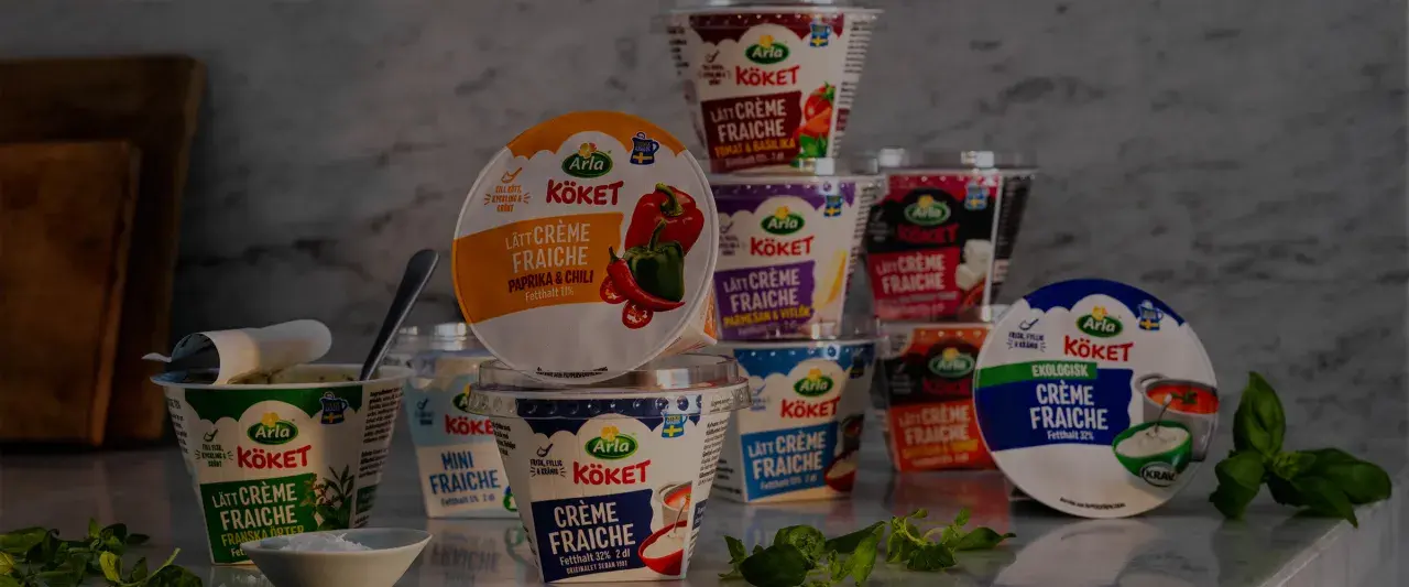 Various Arla Köket crème fraîche tubs, some open, with herbs and a bowl of salt.