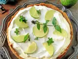 En krämig key lime pie med limeklyftor och mynta på en krispig botten, serverad på ett vackert fat.