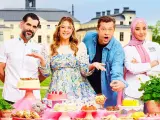 Fyra glada personer poserar vid ett bord fyllt med bakverk. De är med i Hela Sverige Bakar, redo att visa upp sina skapelser.
