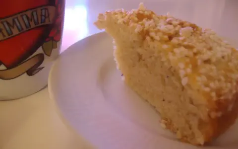 En bit saftig sockerkaka med kardemumma, toppad med nötter, ligger på en vit tallrik bredvid en mugg med texten "MAMMA".