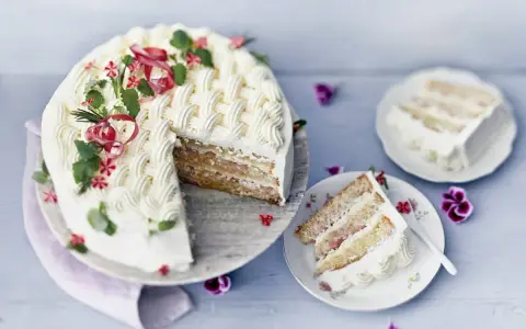 En vacker rabarberkompott tårta med flätmönster av grädde, garnerad med örter och blommor. En bit är upplagd på en tallrik.