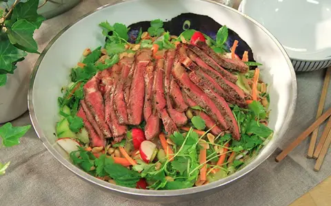 En läcker asiatisk biffsallad med tunt skivad biff, krispiga grönsaker som gurka och morot, färsk koriander och jordnötter.