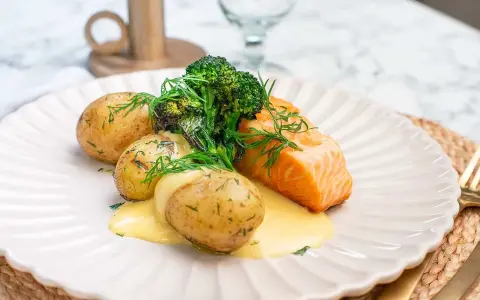 En saftig bit lax med krämig sås, serverad med små, dillkryddade potatisar och fräsch broccoli. En klassisk svensk rätt med lax och potatis.
