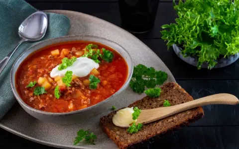 En värmande köttfärssoppa utan tomat, toppad med en klick gräddfil och färsk persilja. Serveras med grovt bröd och smör.
