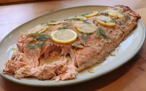 Helstekt lax i ugn, toppad med citronskivor och dill. Perfekt för en festlig middag.