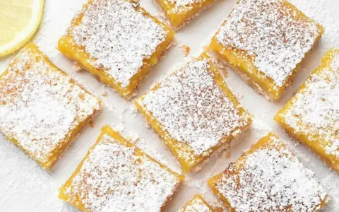 Citronkaka i långpanna, pudrad med florsocker, skuren i fyrkanter. En citronskiva syns i övre vänstra hörnet.