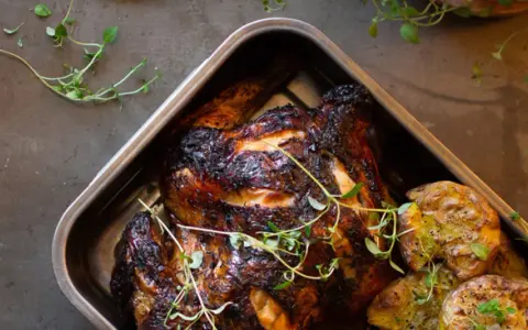 Helstekt kyckling med krispiga potatisar i ugnsform. Perfekt kyckling temperatur ger en saftig och god måltid.